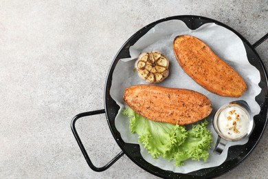 Photo of Tasty cooked sweet potato served in baking dish on grey textured table, top view. Space for text