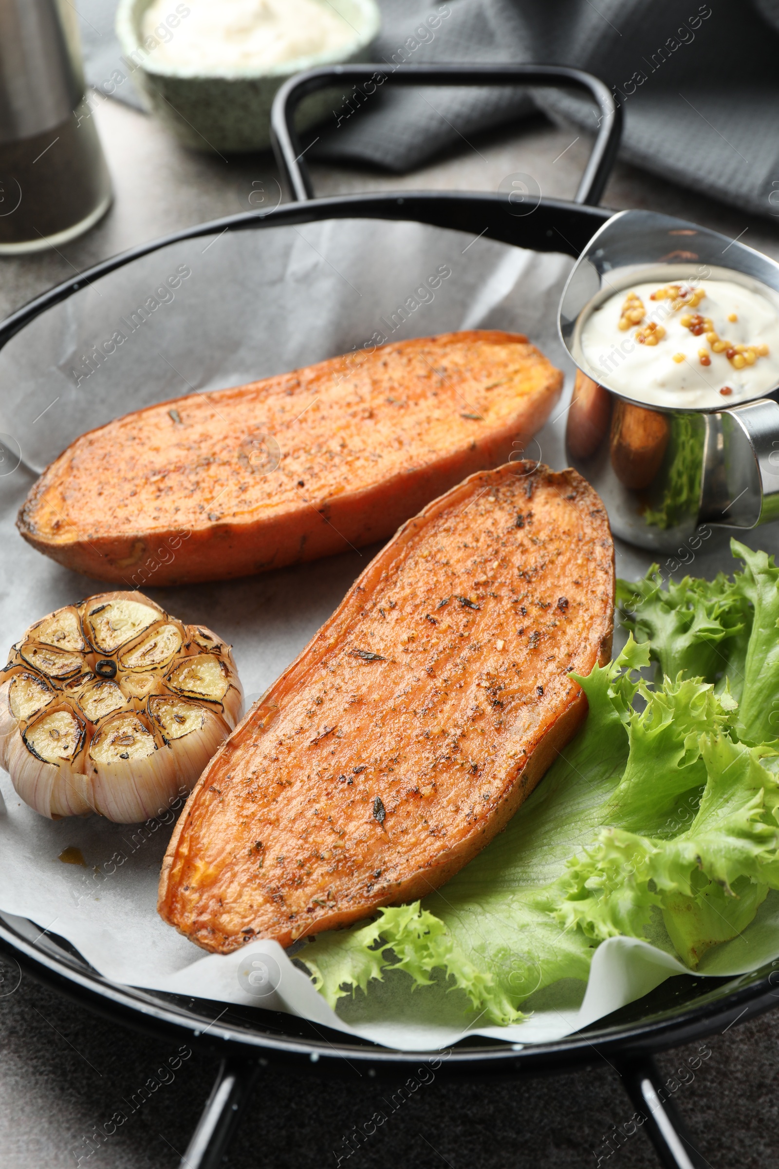 Photo of Tasty cooked sweet potato in baking dish served on grey textured table