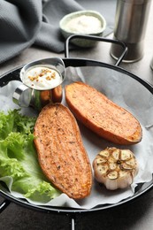 Photo of Tasty cooked sweet potato in baking dish served on grey textured table