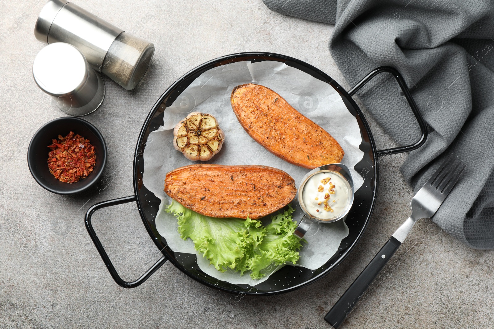 Photo of Tasty cooked sweet potato in baking dish served on grey textured table, flat lay