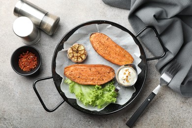 Tasty cooked sweet potato in baking dish served on grey textured table, flat lay