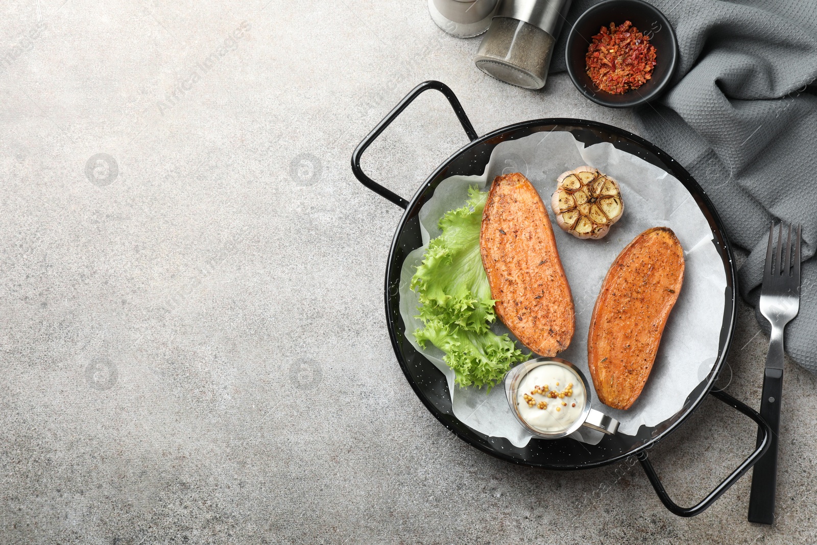 Photo of Tasty cooked sweet potato in baking dish served on grey textured table, flat lay. Space for text