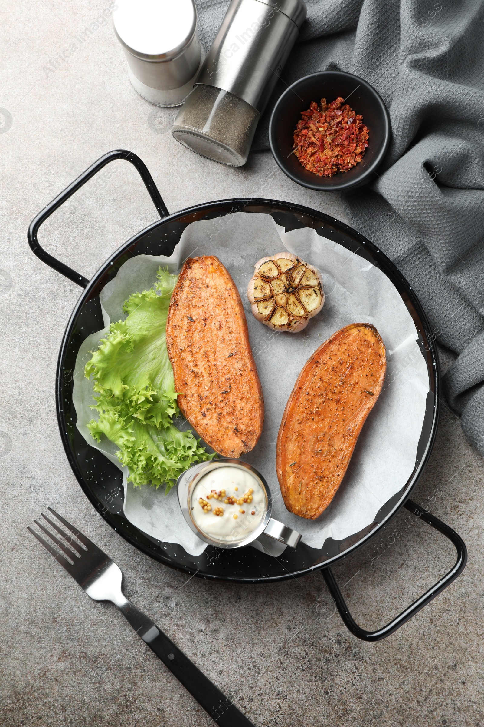 Photo of Tasty cooked sweet potato in baking dish served on grey textured table, flat lay