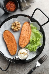 Photo of Tasty cooked sweet potato in baking dish served on grey textured table, flat lay