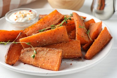 Photo of Pieces of tasty baked sweet potato with microgreens served on white table, closeup