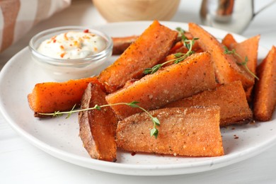 Photo of Pieces of tasty baked sweet potato with microgreens served on white table, closeup