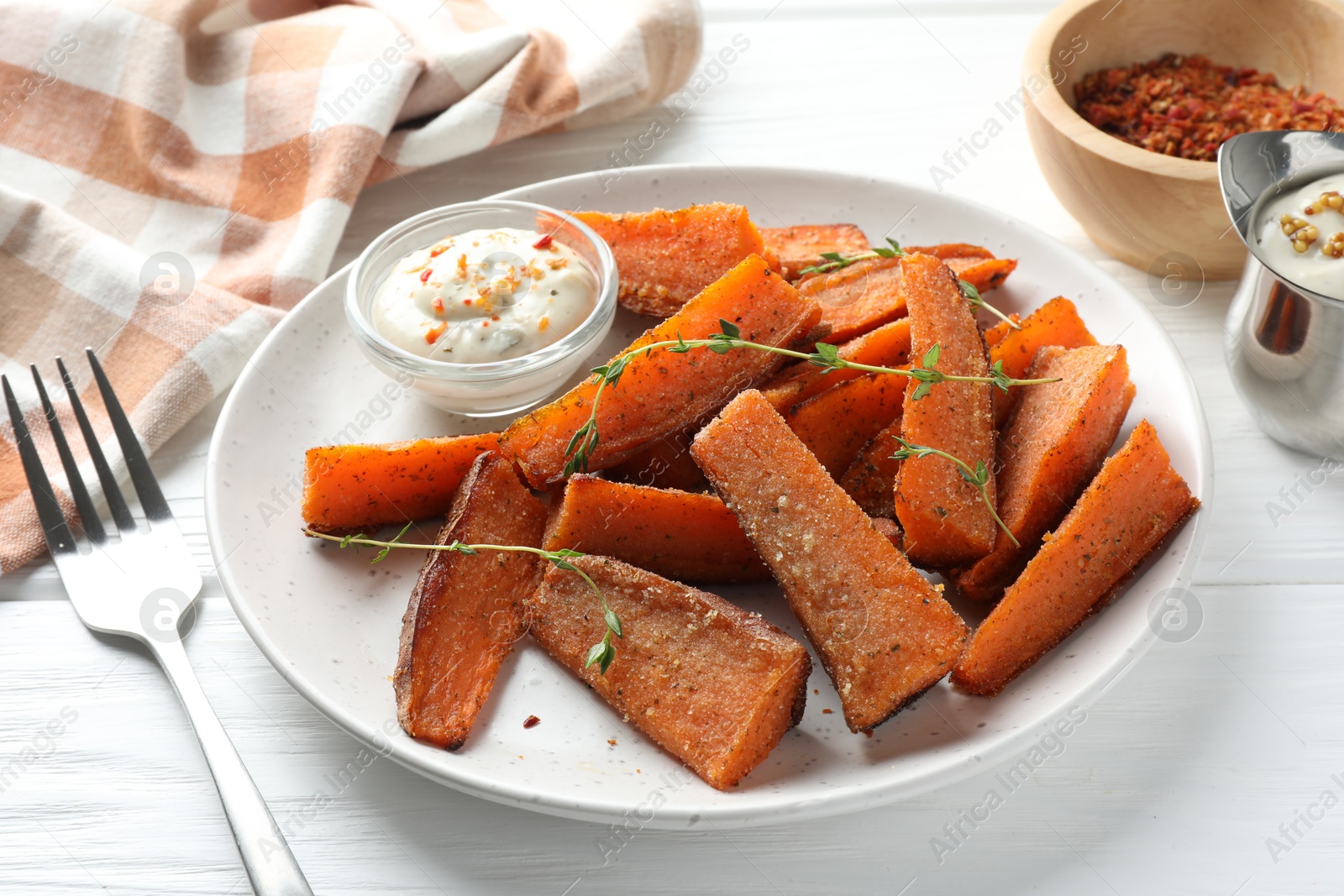 Photo of Pieces of tasty baked sweet potato with microgreens served on white wooden table