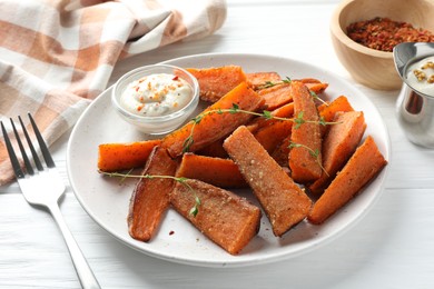 Pieces of tasty baked sweet potato with microgreens served on white wooden table