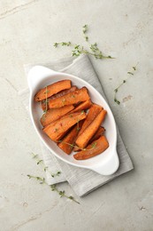 Photo of Pieces of tasty cooked sweet potato in baking dish with microgreens on light textured table, top view