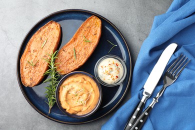 Photo of Halves of tasty baked sweet potato served on grey textured table, flat lay