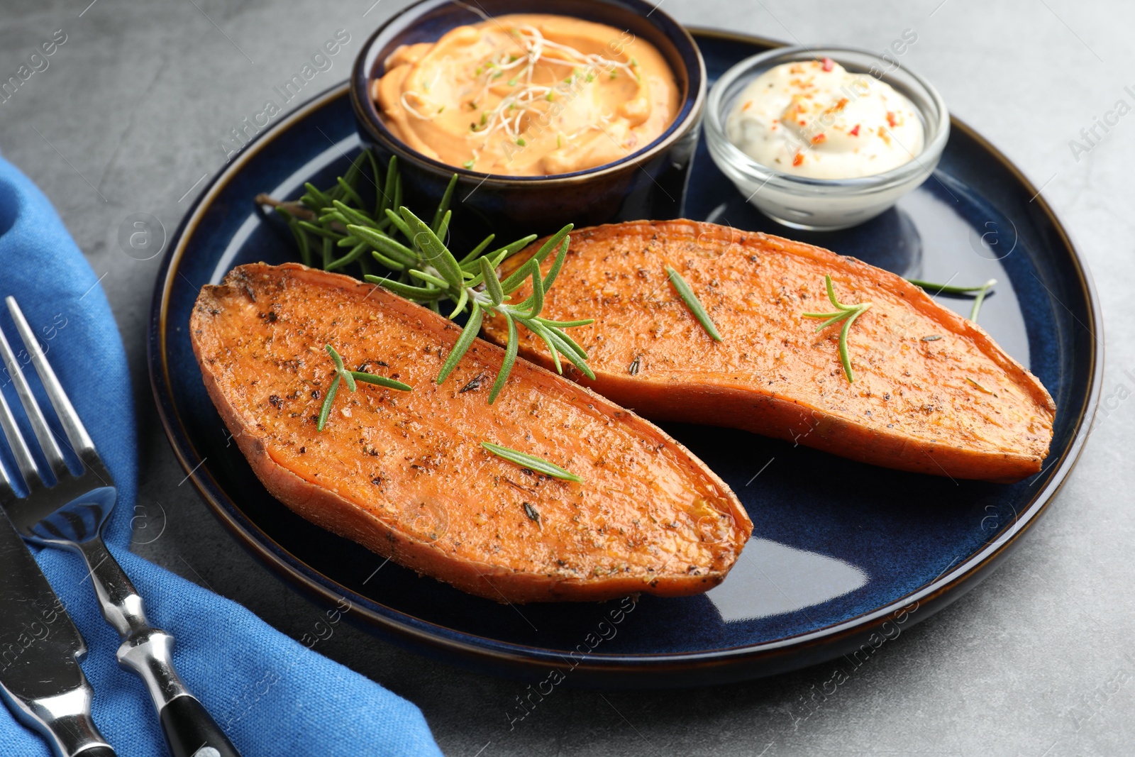 Photo of Halves of tasty baked sweet potato served on grey textured table