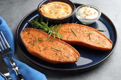 Photo of Halves of tasty baked sweet potato served on grey textured table