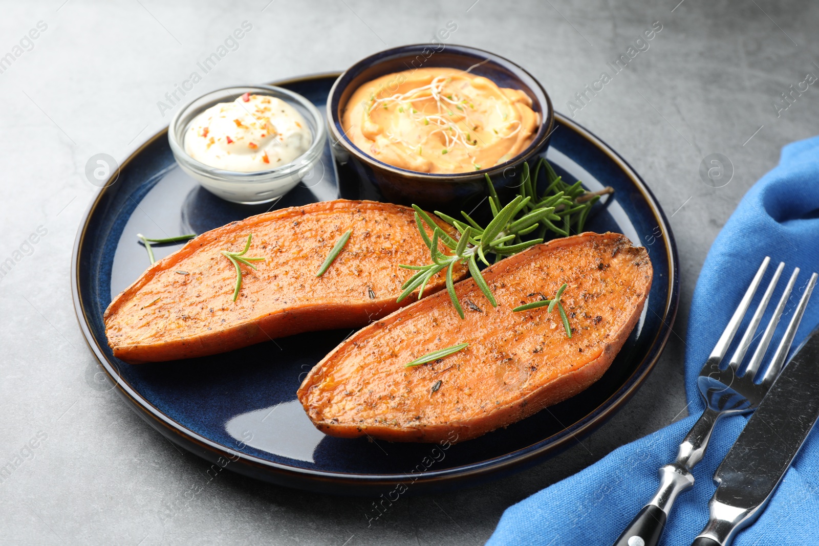 Photo of Halves of tasty baked sweet potato served on grey table