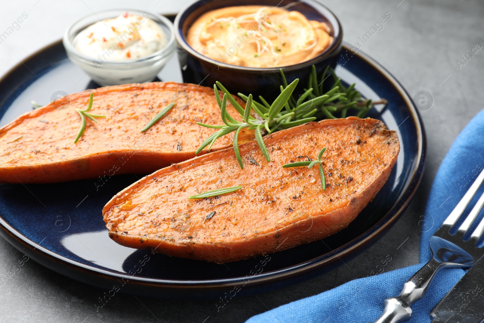 Photo of Halves of tasty baked sweet potato served on grey table, closeup