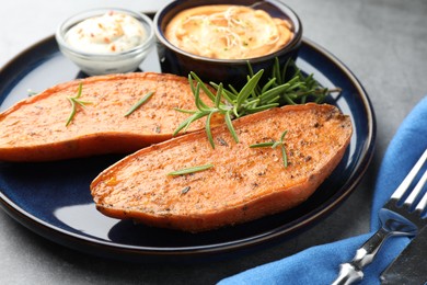 Photo of Halves of tasty baked sweet potato served on grey table, closeup