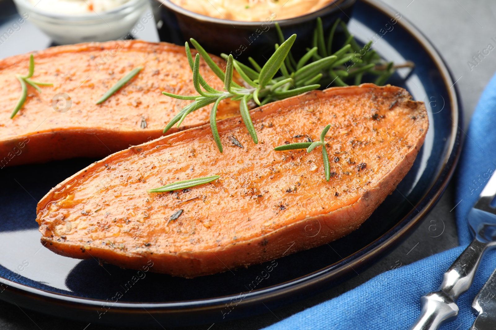 Photo of Halves of tasty baked sweet potato served on grey table, closeup