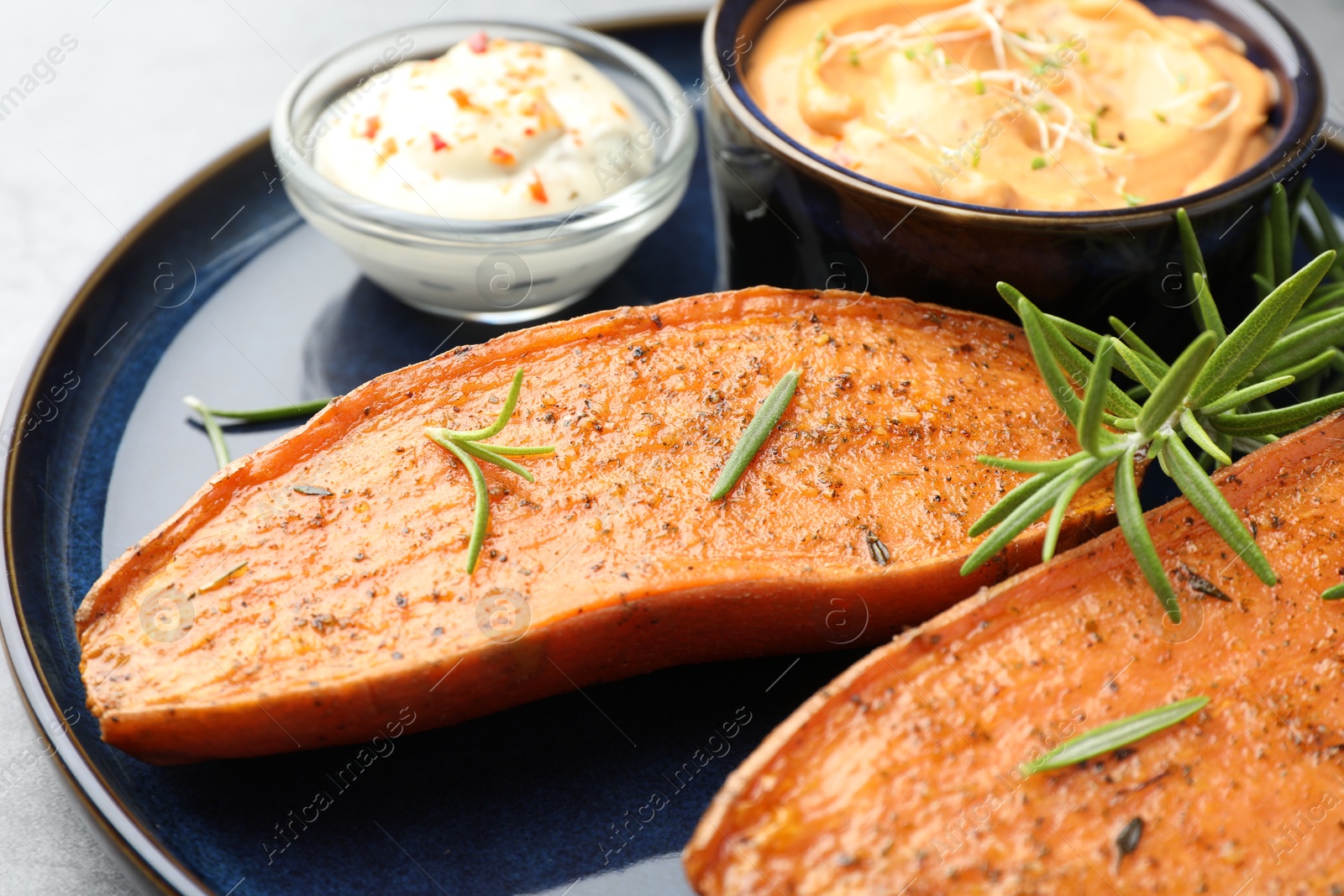 Photo of Halves of tasty baked sweet potato served on grey table, closeup