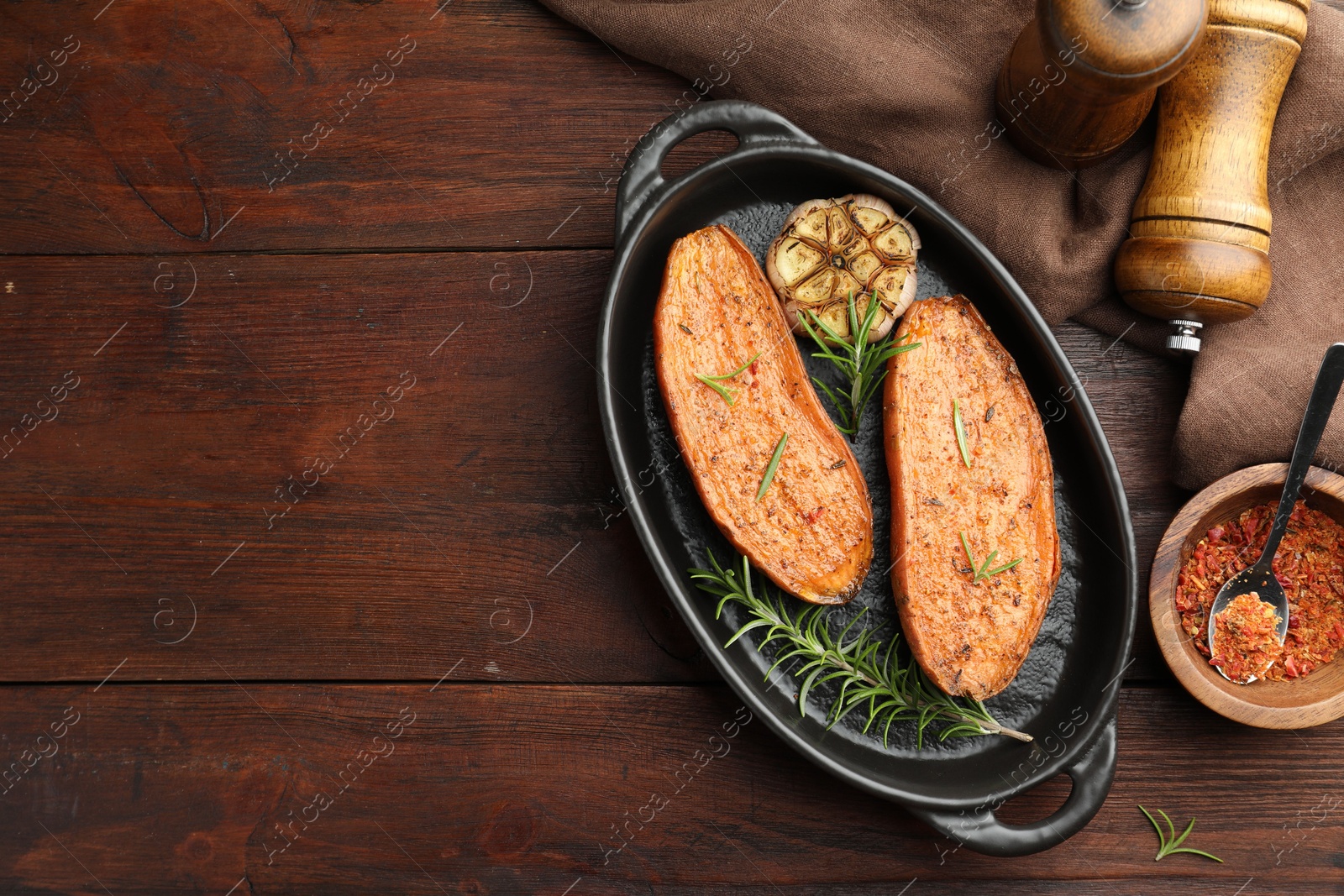 Photo of Halves of tasty cooked sweet potato in baking dish served on wooden table, flat lay. Space for text