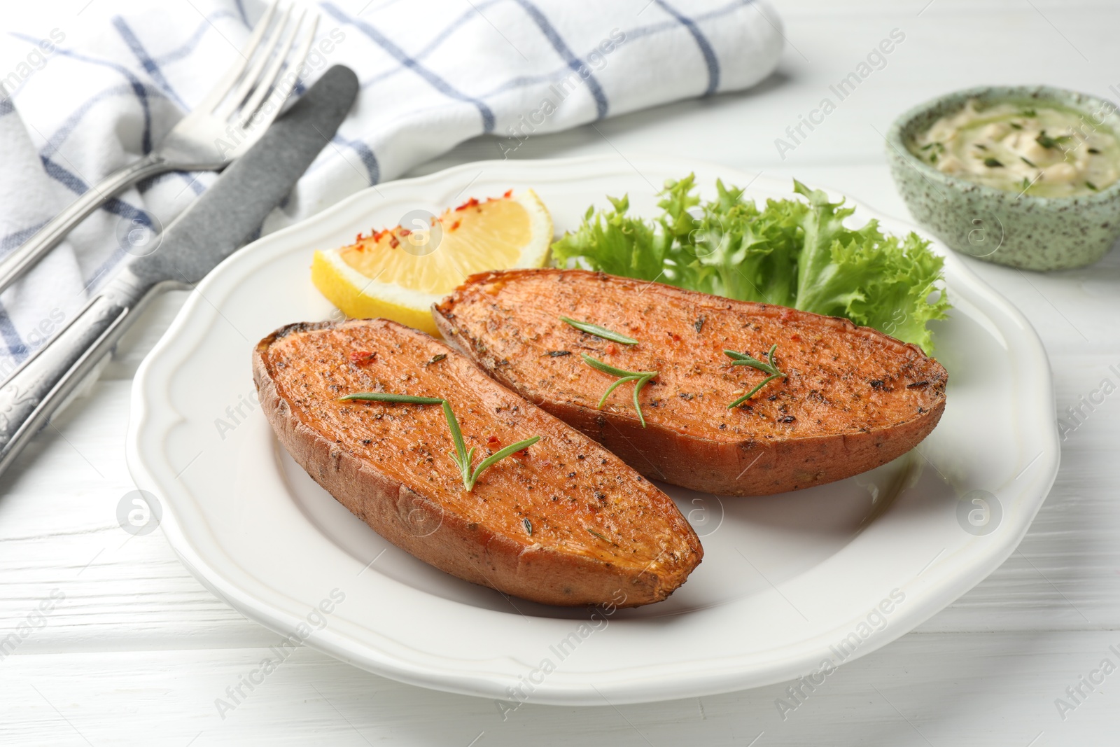 Photo of Tasty baked sweet potato served on white wooden table, closeup