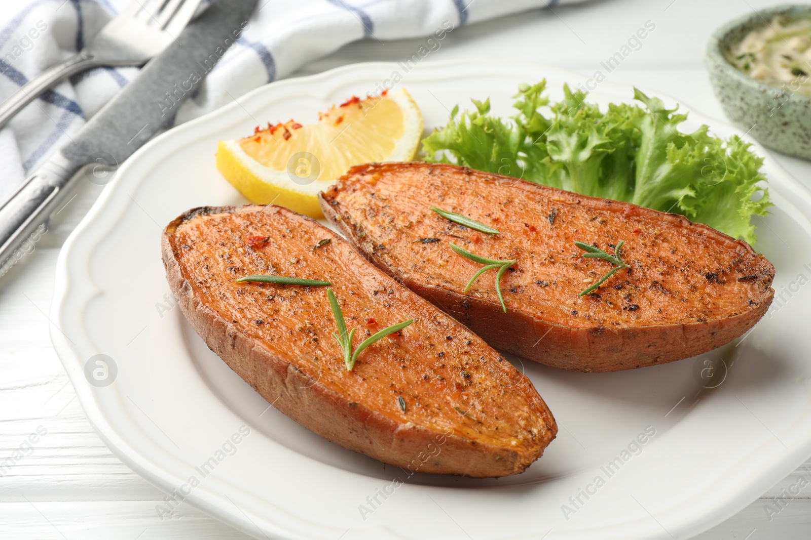 Photo of Tasty baked sweet potato served on white wooden table, closeup