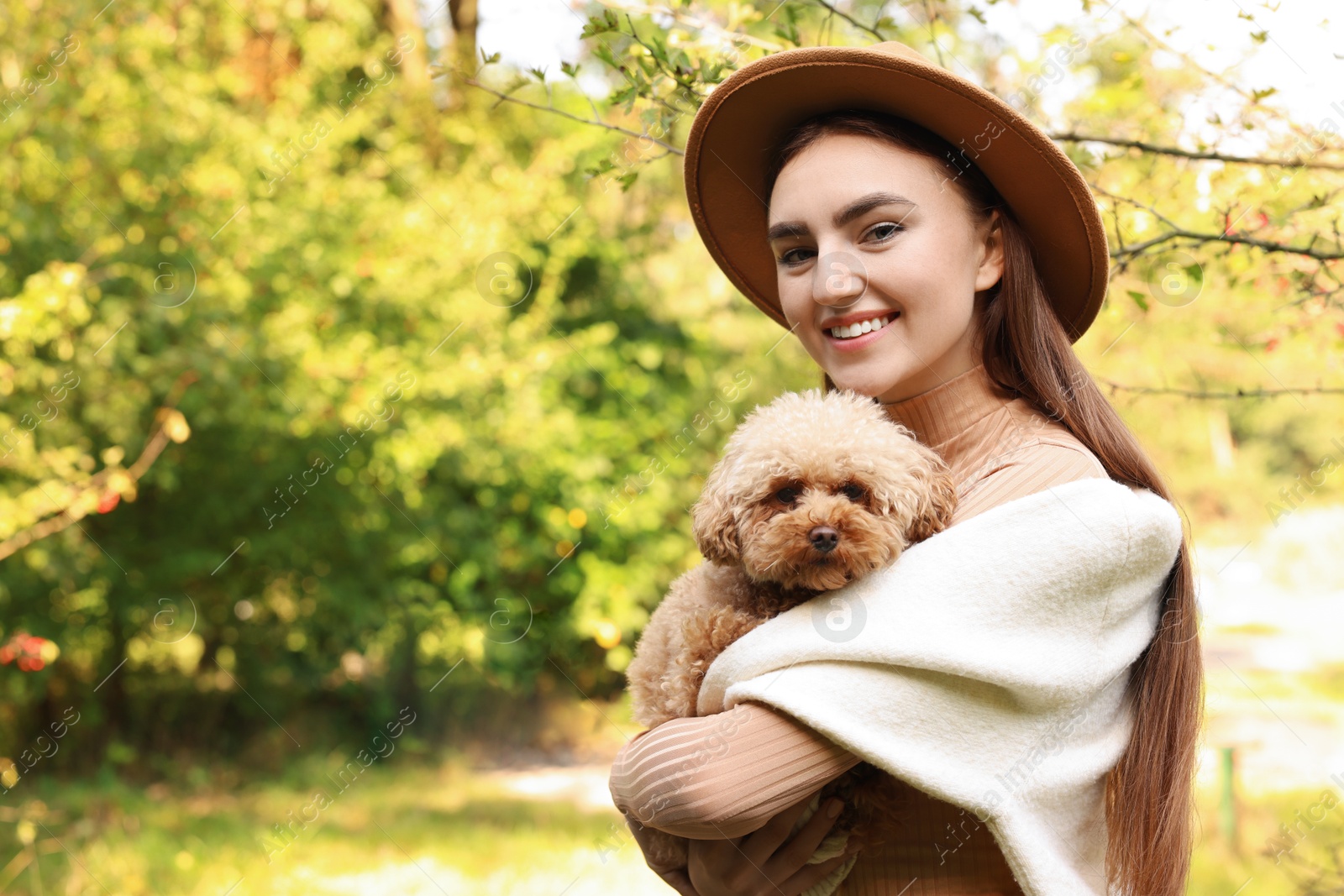 Photo of Smiling woman with cute dog in autumn park. Space for text