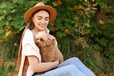 Photo of Smiling woman with cute dog in autumn park. Space for text