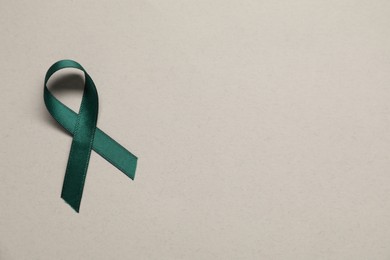 Green awareness ribbon on gray background, top view. Space for text