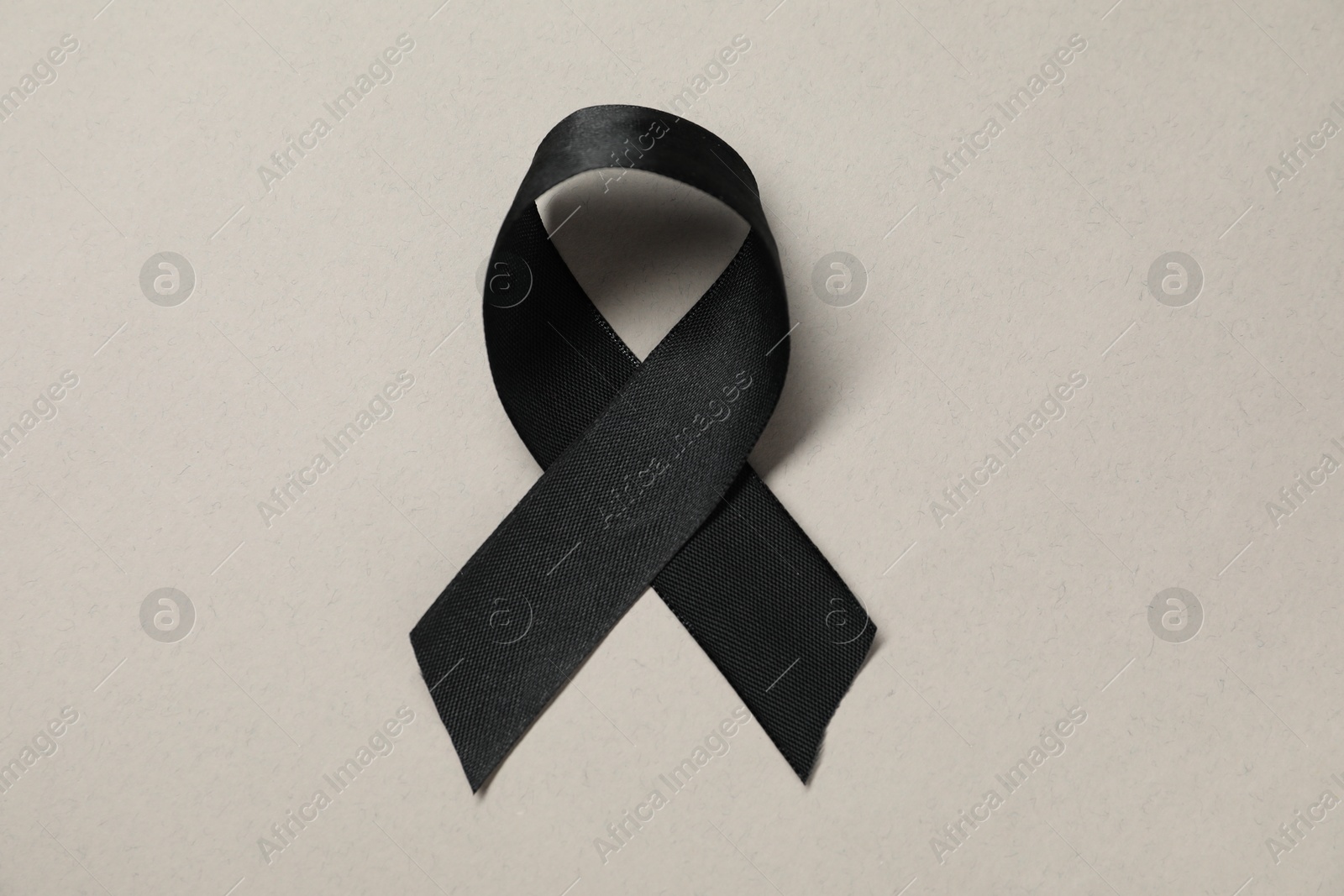 Photo of Black awareness ribbon on gray background, top view