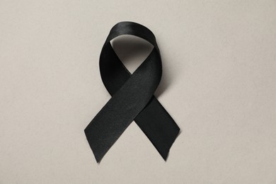 Black awareness ribbon on gray background, top view