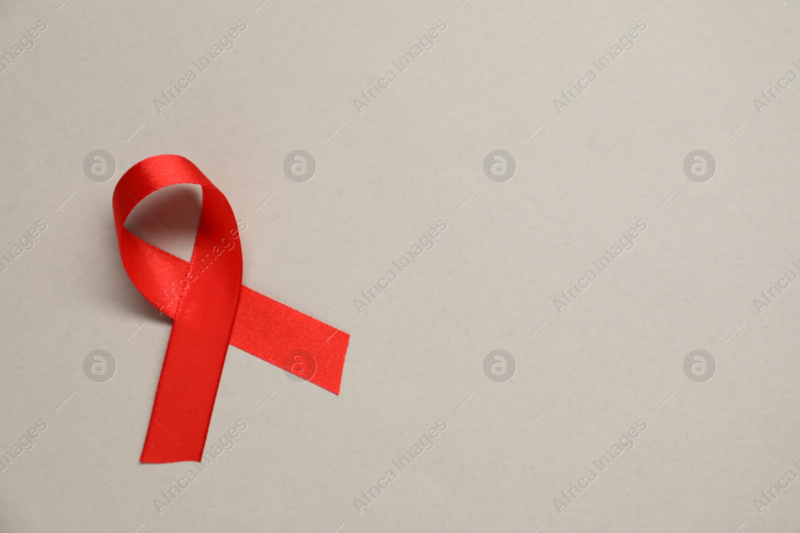 Photo of Red awareness ribbon on gray background, top view. Space for text