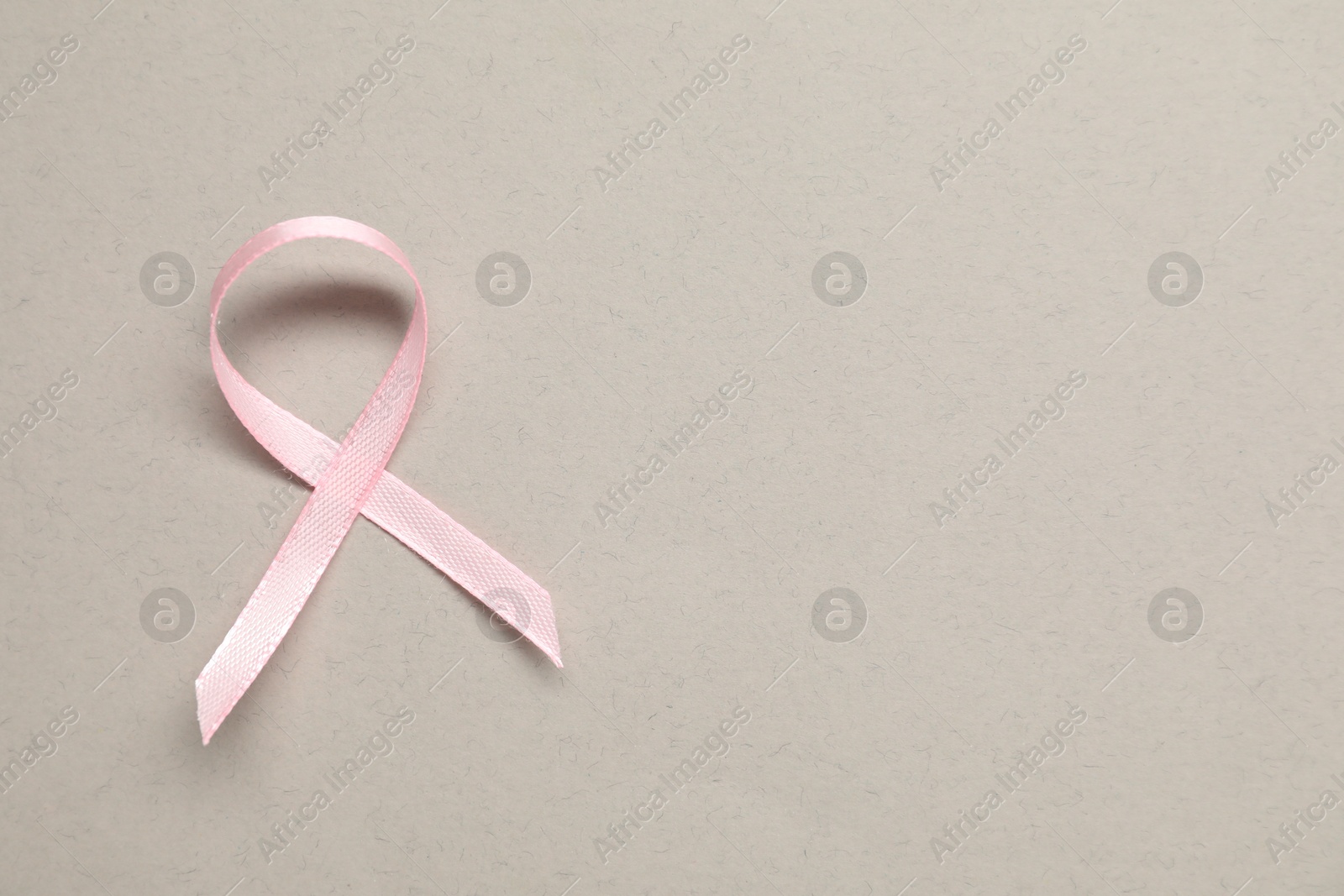 Photo of Pink awareness ribbon on gray background, top view. Space for text