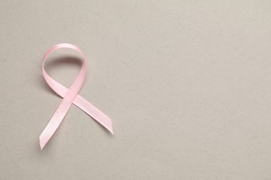 Photo of Pink awareness ribbon on gray background, top view. Space for text