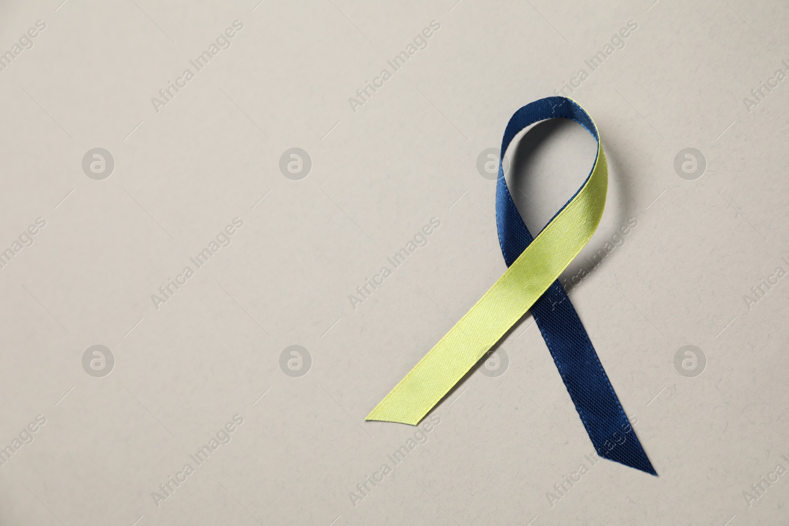 Photo of Yellow and blue awareness ribbon on gray background, top view. Space for text