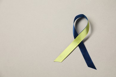 Photo of Yellow and blue awareness ribbon on gray background, top view. Space for text