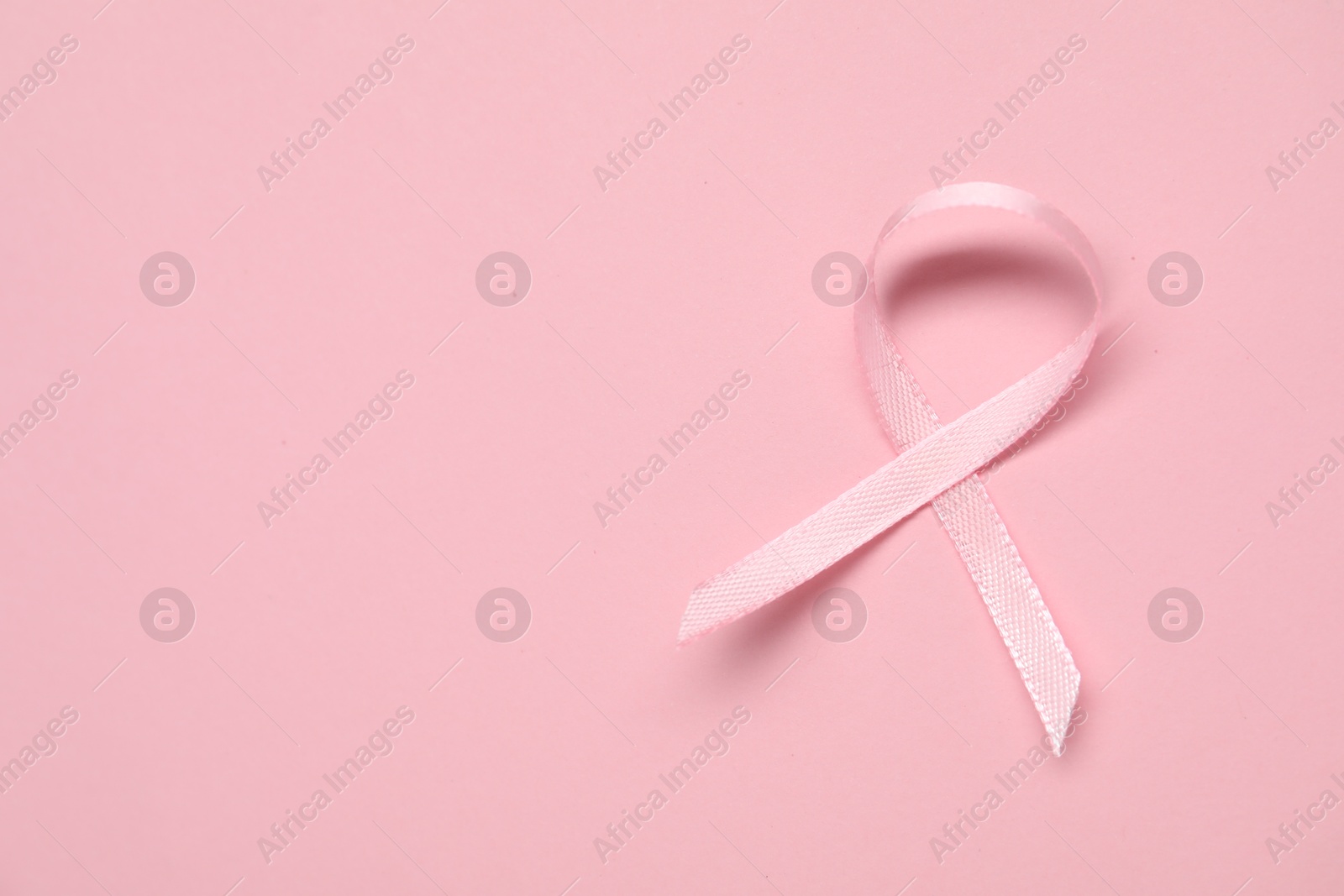 Photo of Pink awareness ribbon on color background, top view. Space for text