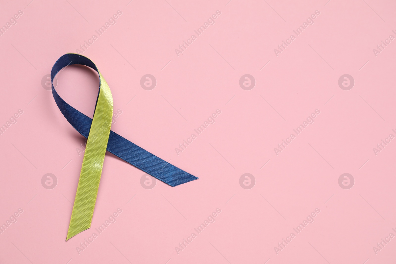 Photo of Yellow and blue awareness ribbon on pink background, top view. Space for text