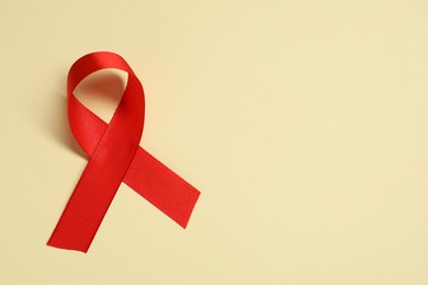 Red awareness ribbon on yellow background, top view. Space for text