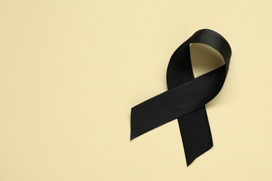 Photo of Black awareness ribbon on yellow background, top view. Space for text