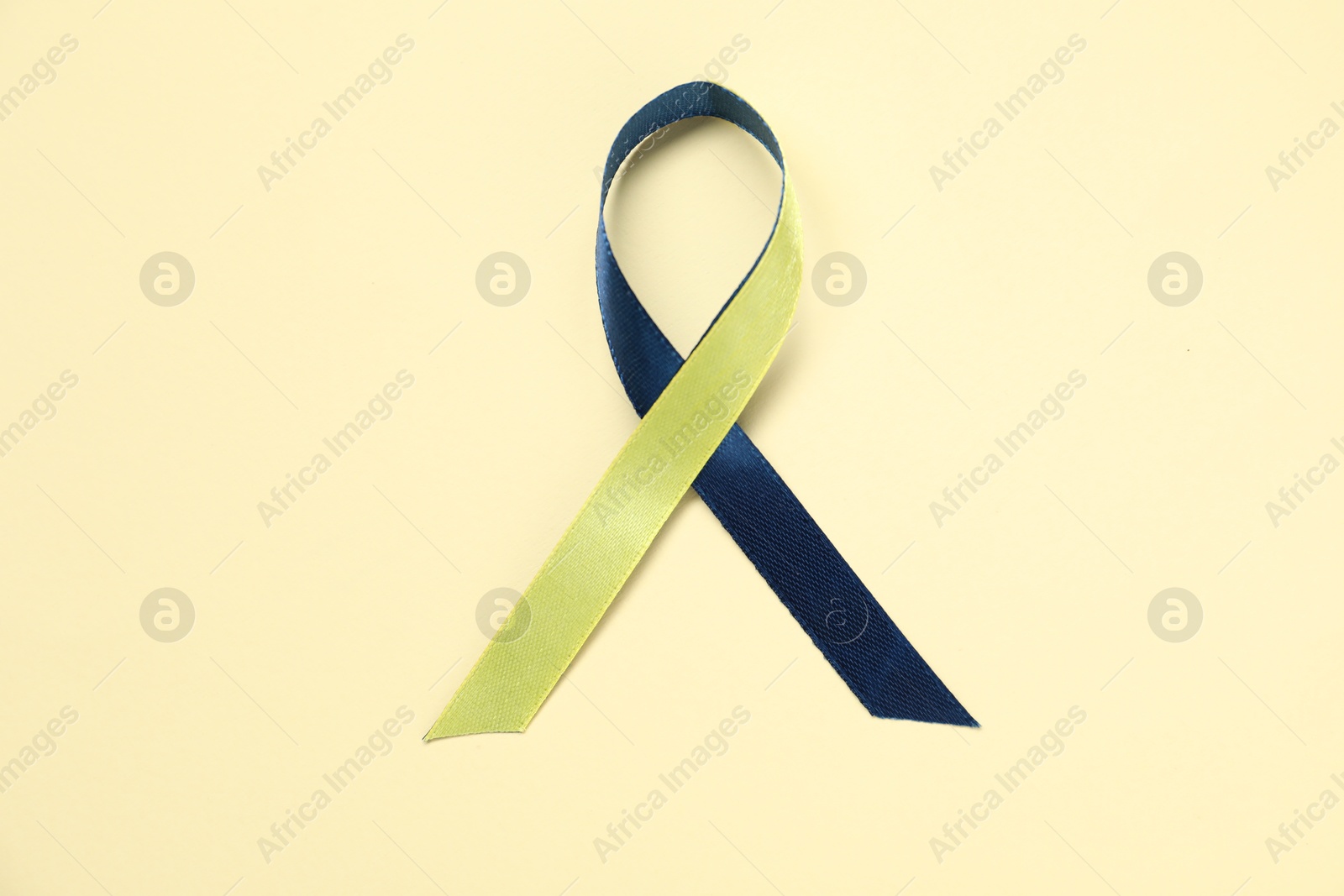 Photo of Yellow and blue awareness ribbon on color background, top view