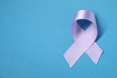 Violet awareness ribbon on blue background, top view. Space for text