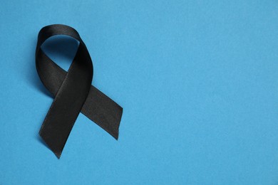 Black awareness ribbon on blue background, top view. Space for text