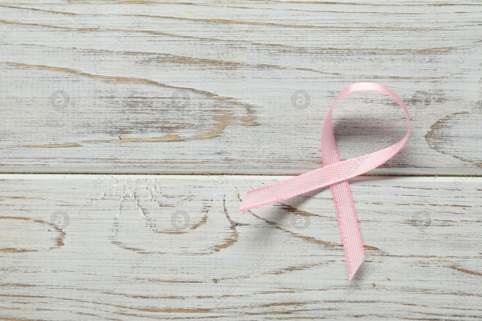 Photo of Pink awareness ribbon on wooden background, top view. Space for text