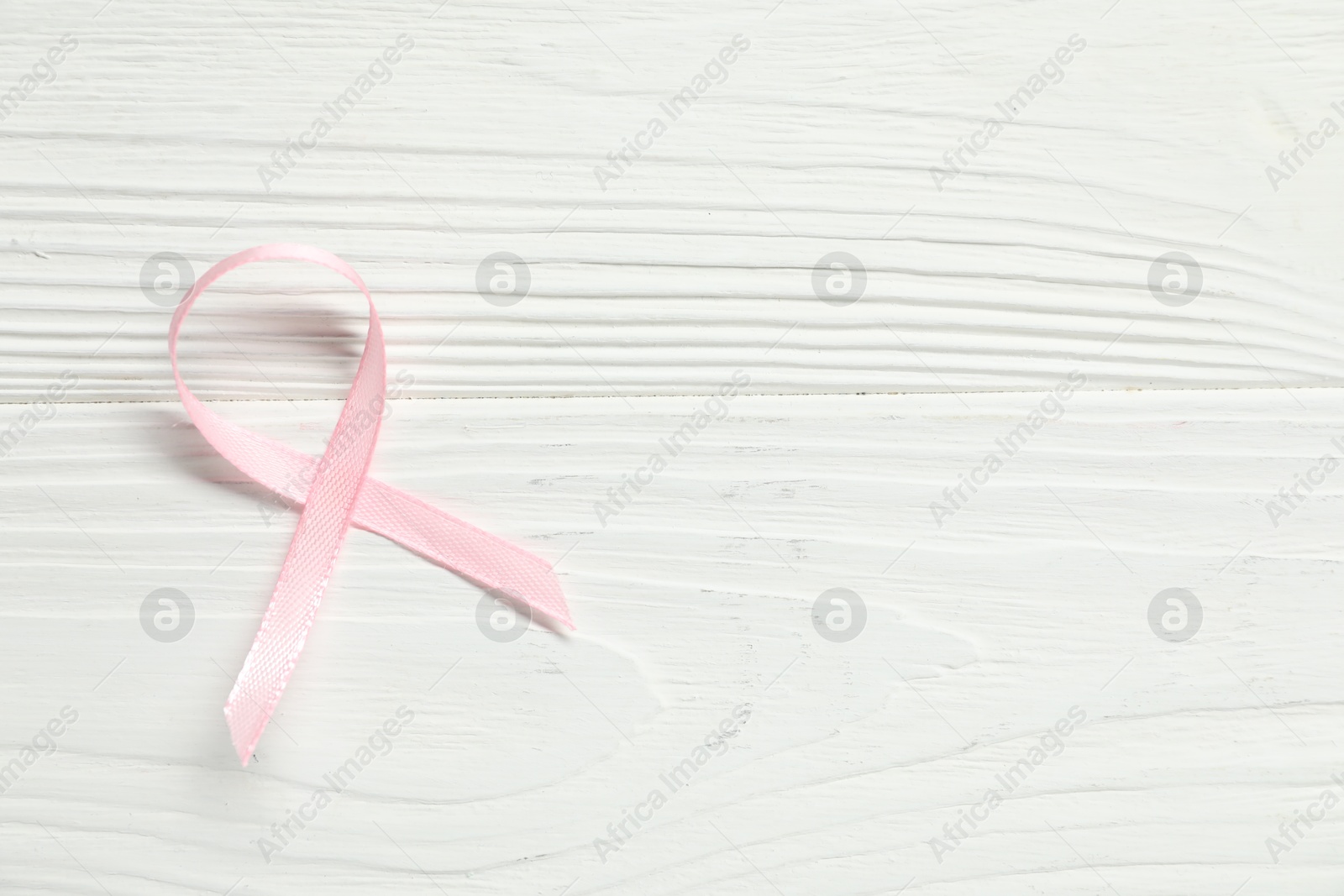 Photo of Pink awareness ribbon on wooden background, top view. Space for text