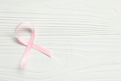 Photo of Pink awareness ribbon on wooden background, top view. Space for text