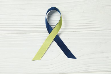 Yellow and blue awareness ribbon on wooden background, top view