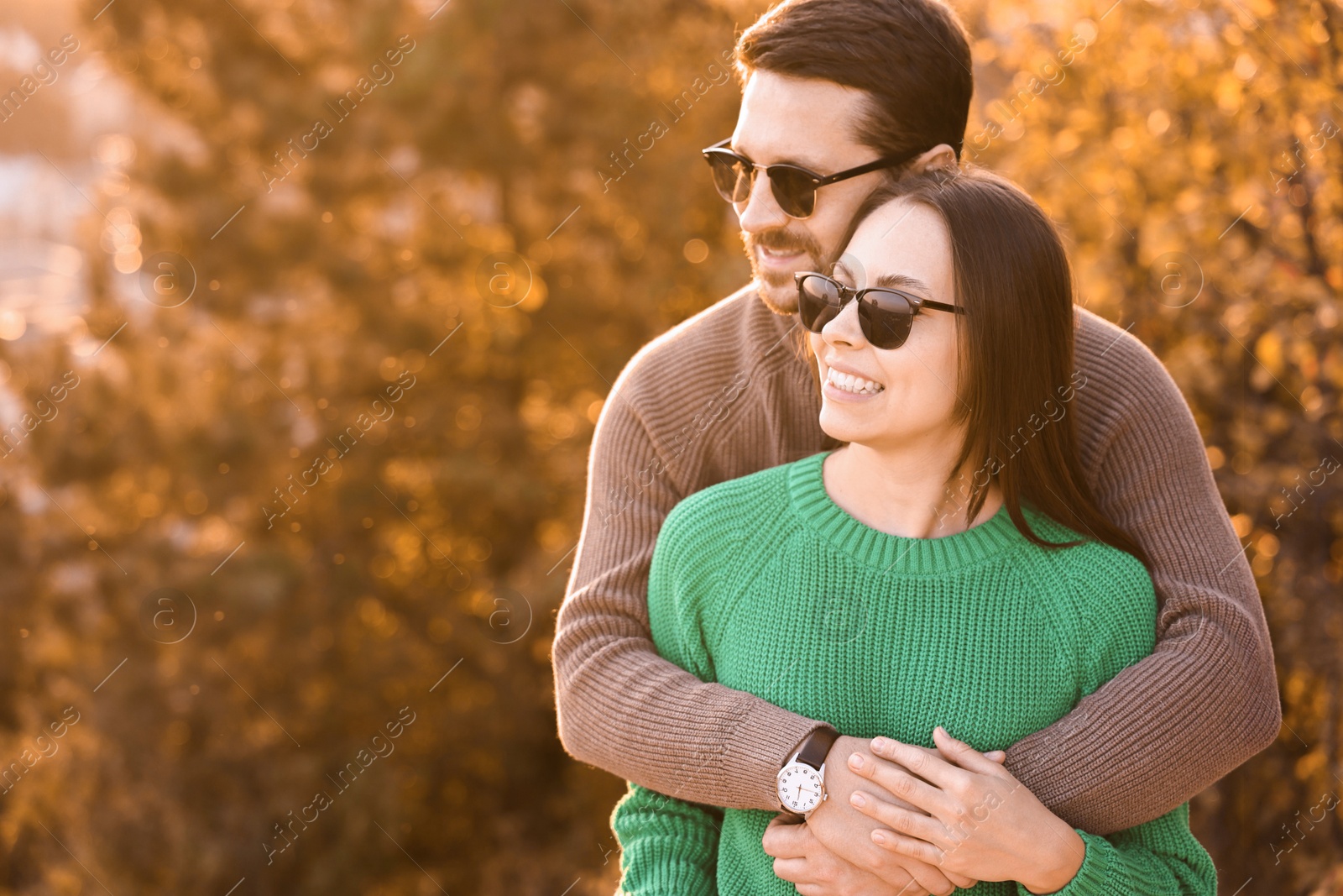 Photo of Beautiful couple hugging outdoors in autumn evening, space for text