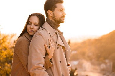 Beautiful couple enjoying their time together outdoors in autumn evening, space for text