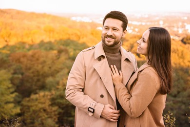 Beautiful couple spending time together outdoors on autumn day, space for text