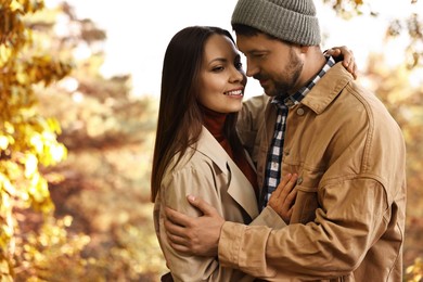 Beautiful couple hugging outdoors on autumn day, space for text