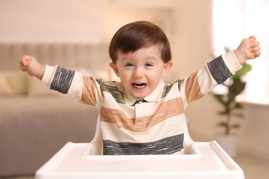 Photo of Cute little kid sitting in high chair at home